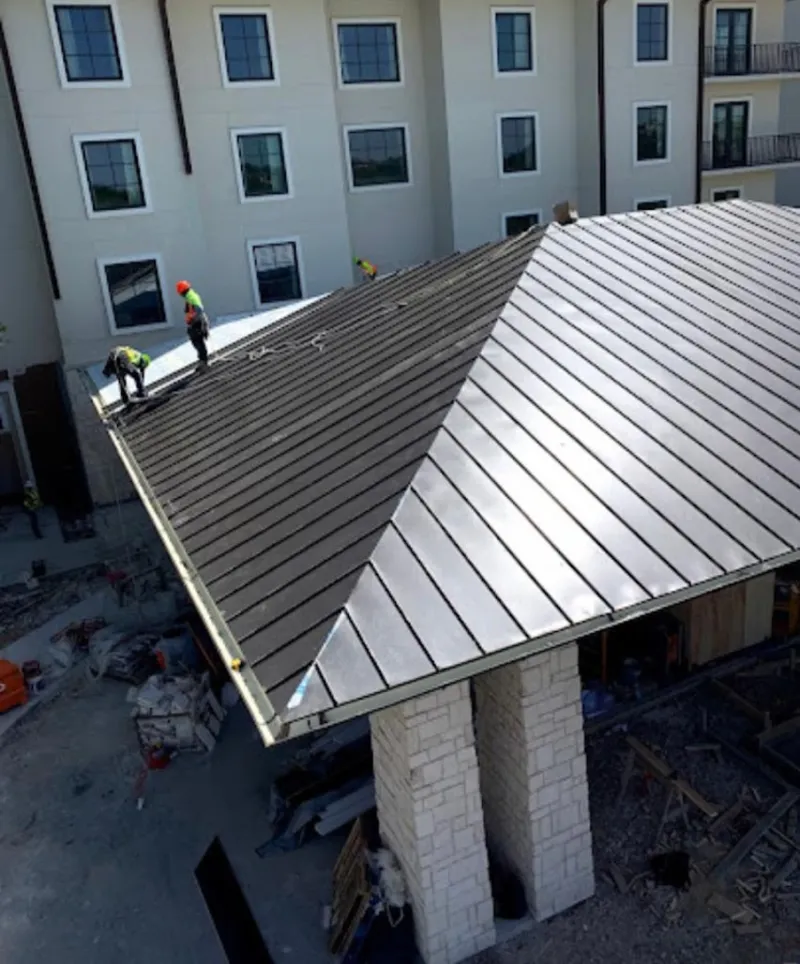 Crew installing standing seam metal roof panels on a commercial project in Annapolis Neck